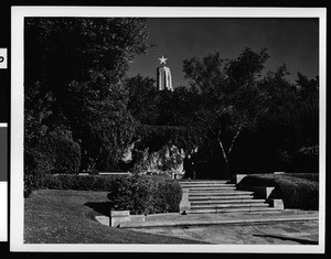 "The Mystery of Life" statue in Forest Lawn Memorial Park, showing a building with a star at its top in the background, Glendale, ca.1920