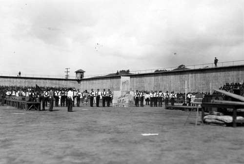 Prisoners in formation with "Olympic Club We Thank You" banner, San Quentin Little Olympics Field Meet, 1930 [photograph]