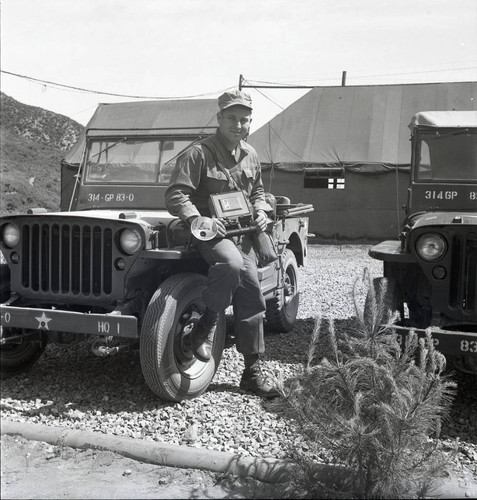 Williams posing with camera and jeep