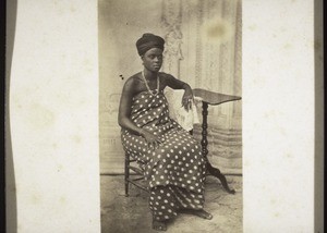 Ga woman with head-tie and her hair-style showing above it, rings on her fingers, ears and toes etc