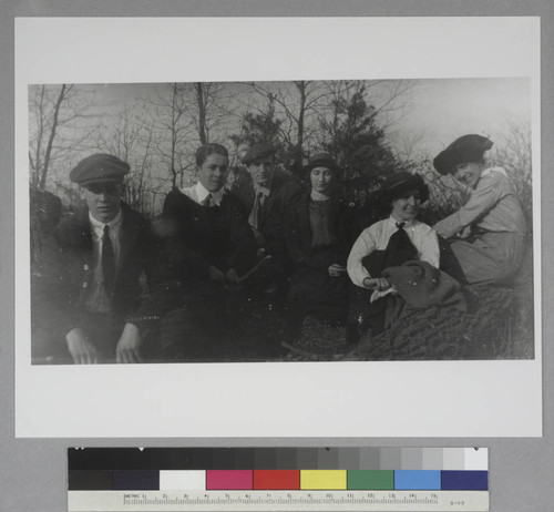 Edwin Hubble seated outside with two unidentified teenage boys and three young women, seated on rocks, outdoors