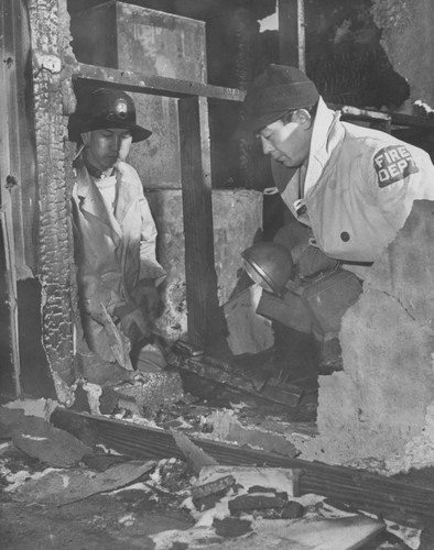 [Two members of the Fire Prevention Squad inspecting remains of dormitory fire at Heart Mountain incarceration camp]