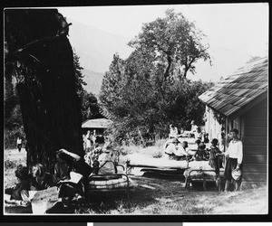 People resting out on cots in front of a cabin, ca.1920