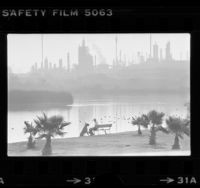 Lake scene in park with oil refinery in background in Harbor City, Calif., 1979