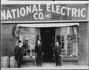 Three men standing in front of the National Electric Company Building, ca.1895