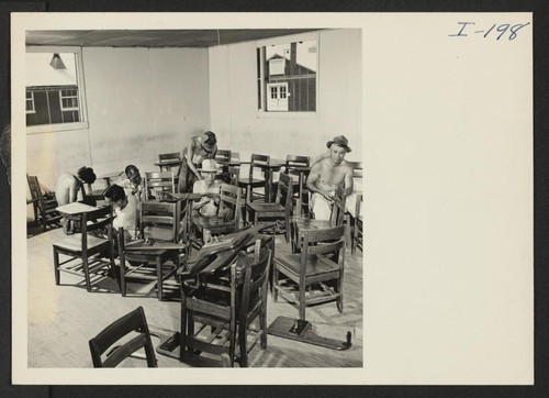 Closing of the Jerome Center, Denson, Arkansas. A recruited crew of Jerome evacuees remove the arms from the high school classroom desks prior to crating them and shipping them to other centers. Photographer: Iwasaki, Hikaru Denson, Arkansas
