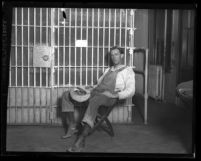 Charles Wesley Way dressed in overalls, sitting in front of jail cell after his arrest for threatening to shoot oil workers in Los Angeles, Calif., 1925