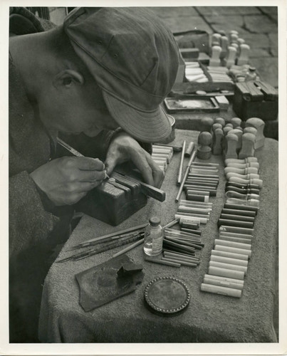 Man carving and selling ink stamps in the market