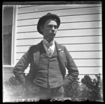 Young man in front of house, hands in pockets