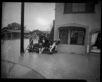Adults and children ride on wooden raft in flood waters, Long Beach, 1930s