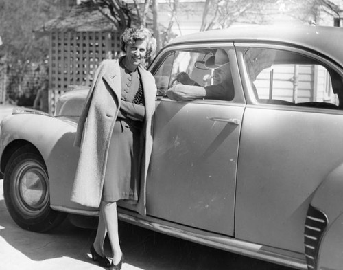 Lady standing by a man in a car
