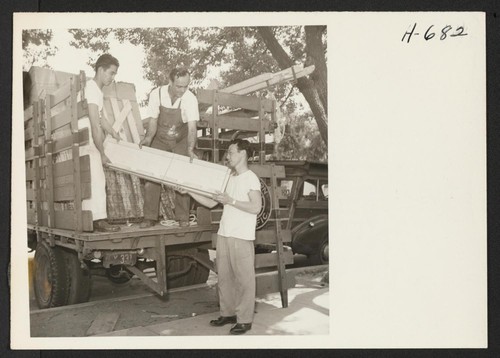 Returnees to Pasadena assist in unloading personal property from the Pacific Railroad truck at the Pasadena Hostel. The Pasadena Hostel