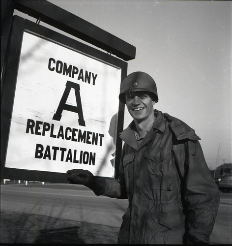 Soldier posing with sign reading "Company A Replacement Battalion" at Camp Stoneman