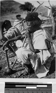 Man sitting on the ground smoking a pipe, Africa, 1933