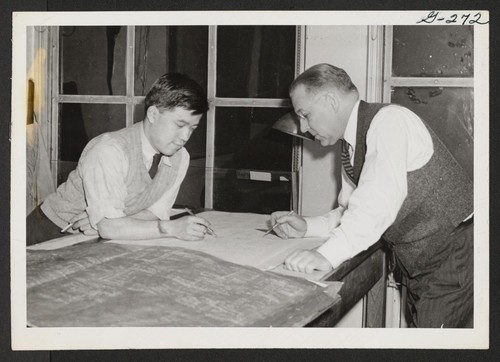 Checking construction plans in the New York Office of an architectural firm is Sunao John Iwatsu with a fellow worker