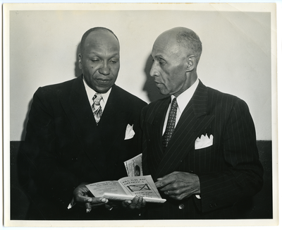 Frederick M. Roberts standing with unidentified man while they both look at a document, "Kill This Ad On Nov 5"