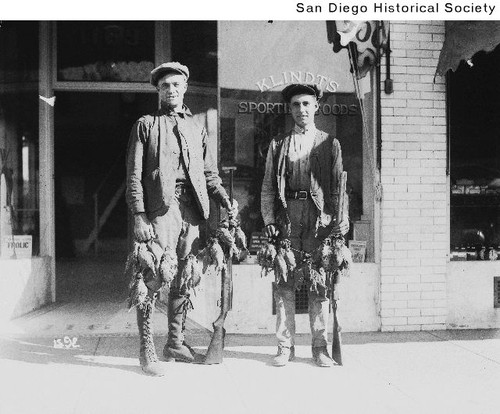 Two quail hunters standing in front of Klindt's Sporting Goods store