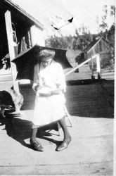 Eloise Miller Riddell reading on an outside deck and holding an umbrella, about 1930