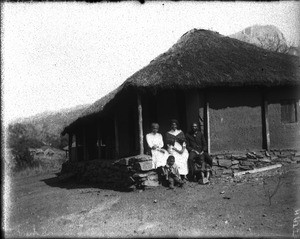 African family in front of a building with a thatched roof, Shilouvane, South Africa