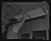 Man working on light fixture, California Labor School