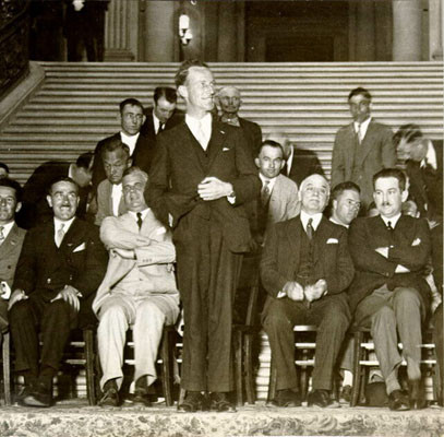 [Smith Kingsford speaking in front of a crowd in the rotunda of City Hall]