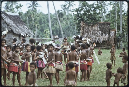 Dance: decorated children with short doba skirts and flattened pandanus leaves for circle dance, younger children play nearby