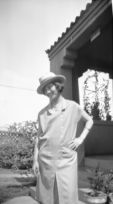 Young woman in hat standing in front of house