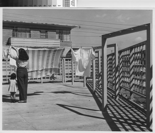 Photograph of a woman and small child hanging laundry at William Mead Homes