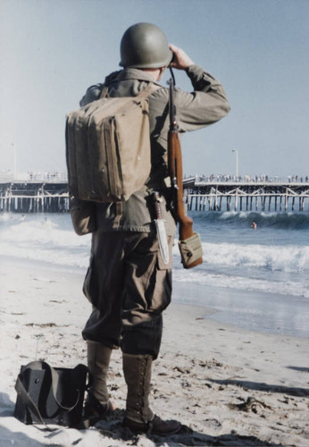 Re-enactor in World War II Army uniform looking at the horizon with a pair of binoculars during the reenactment of D-Day landing, Santa Monica, Calif