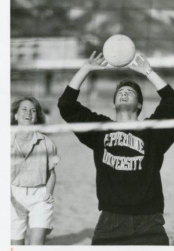 Photograph of a man and woman student playing volleyball