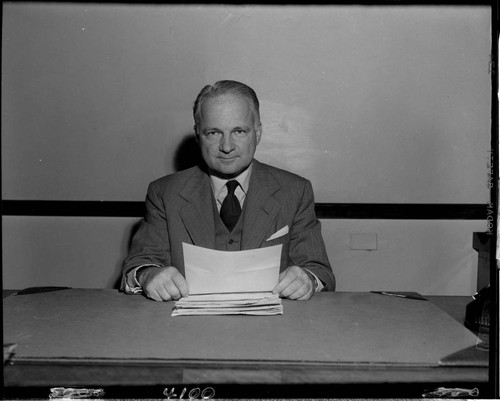Man seated at desk reading printout
