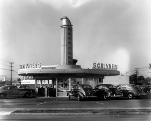 A view of Scrivner's Restaurant which is a circular building cars parked around it