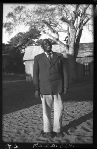 African man standing in front of a building, Mozambique, ca. 1940-1950