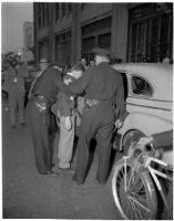 Police arresting Frank Bincia in front of Pacific Press, Inc. due to an altercation with John Sullivan, Los Angeles, August 6, 1946