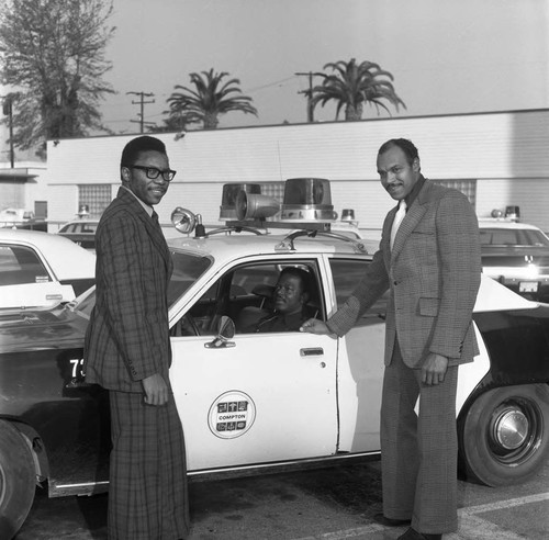 Thomas W. Cochee posing next to a police car with others, Los Angeles, 1974