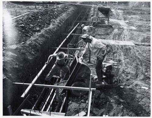 Construction of the Santa Monica Municipal Pool showing workers using a power cart on footing pour, July 25, 1950
