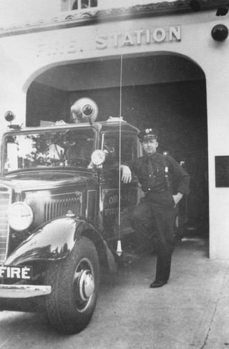 Floyd Higgins posed next to fire truck at Orange Fire Station on South Olive Street, Orange, California, 1963
