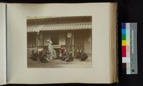 Photoraph of group kneeling before man in eboshi hat in front of a palanquin