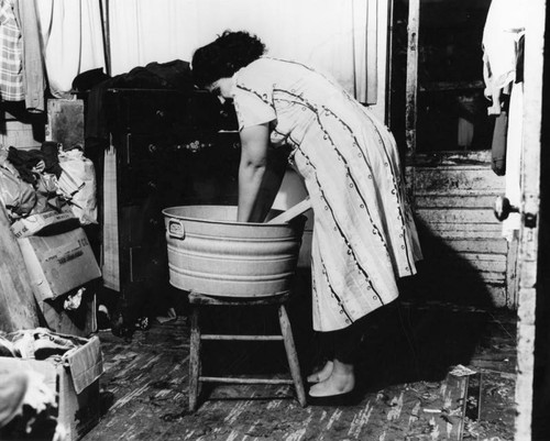 Mrs. Gillen washes clothes, slum dwelling
