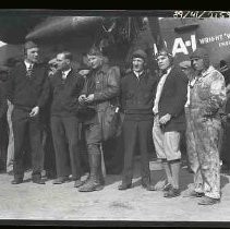 Six men standing in front of an airplane