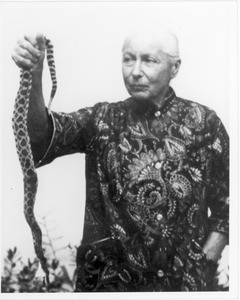 Marta Feuchtwanger holds the end of a snake in her right hand, ca. 1970-1980