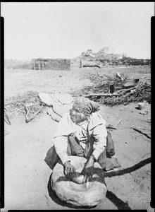 Cahuilla Indian woman grinding corn in a stone mortar at Cahuilla, 1897