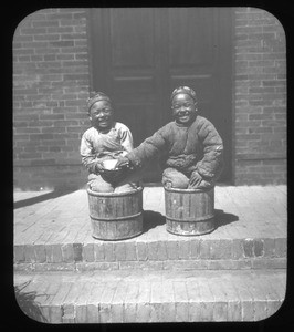 Two smiling boys sitting in wooden buckets, China, ca. 1918-1938