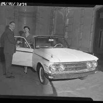 Man and woman standing next to a covnertible car