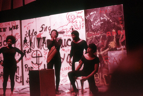 Play performance with four actors in front of a spray painted backdrop