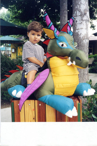 Child sitting on a colorful toy dragon, 1997