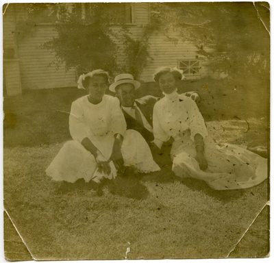 Man and two women sitting in yard