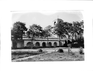 General view of the arches and bell tower of Mission San Juan Bautista, from the front, 1927