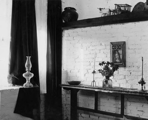 Sideboard with flowers and candle, kerosene lamp in the Avila Adobe