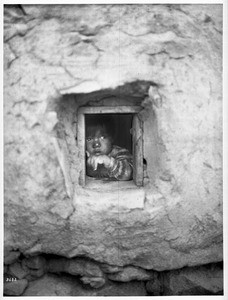 Small Hopi Indian child peering out a window, ca.1900